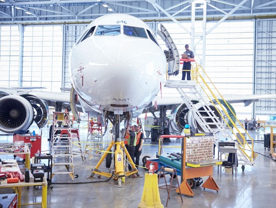 Técnicos realizando mantenimiento a un Airbus A320 en hangar